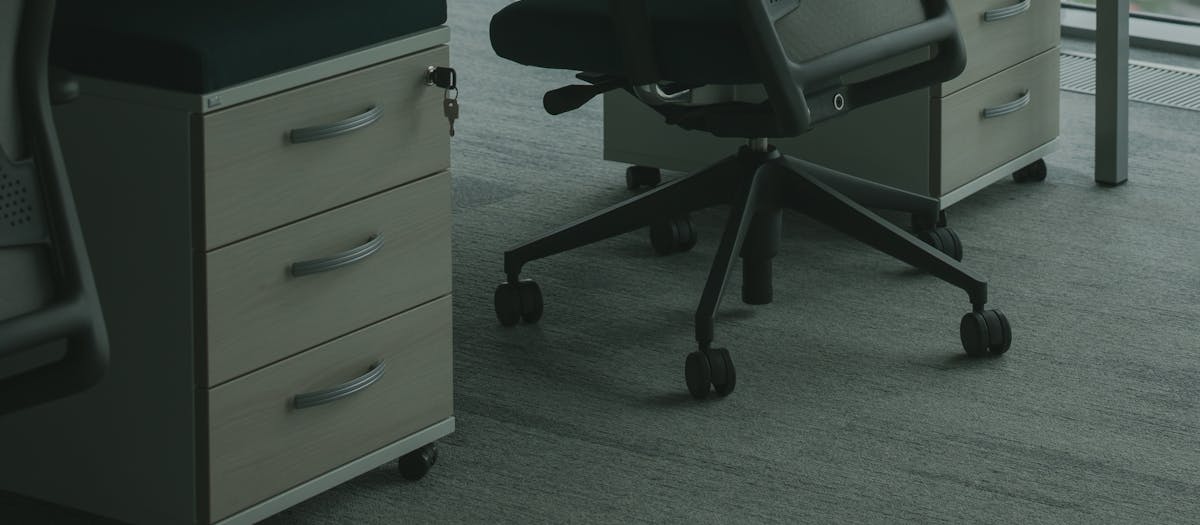 A sleek office setup featuring ergonomic chairs and drawer units in a well-lit space.