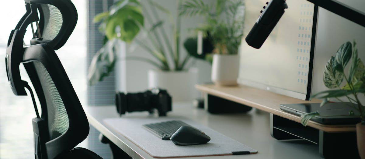 Stylish home office setup with ergonomic chair, plants, and tech accessories creating a modern work environment.